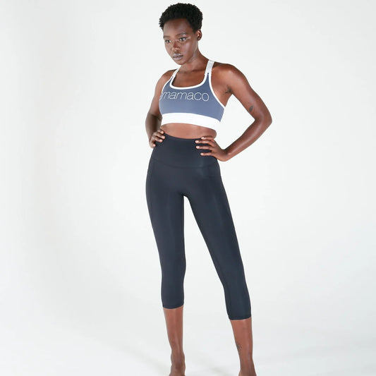 A woman comfortably dressed in soft activewear, holding a baby, looking relaxed and content.